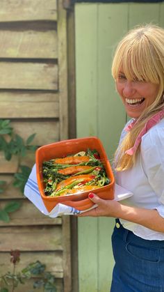 a woman holding a dish with vegetables in it