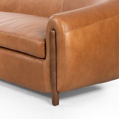 a brown leather couch sitting on top of a white floor next to a wooden frame