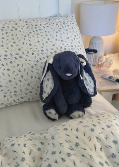 a blue stuffed animal sitting on top of a bed next to pillows and night stands