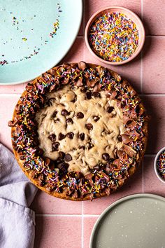 a cookie pie with sprinkles and chocolate chips on the side next to two bowls