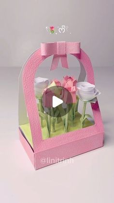 an origami box with flowers in it and a bow on the top that is pink