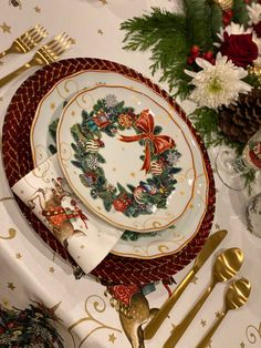 a christmas themed table setting with gold utensils and napkins on the plate