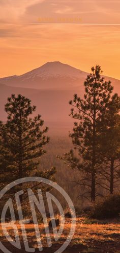 the sun is setting over some trees and mountains