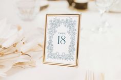 the table numbers are displayed in an ornate frame on top of a white table cloth