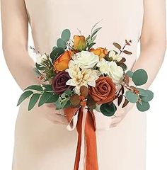 a woman holding a bouquet of flowers in her hands and an orange ribbon around her waist