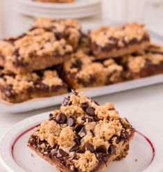 chocolate chip cookie bars stacked on top of each other in front of another dessert plate