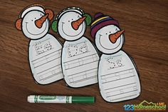 three snowmen are lined up with writing paper on the table next to a marker