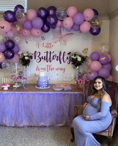 a pregnant woman sitting in front of a table with balloons