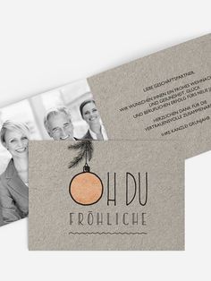 two business cards with the words hou frohliche on them and an orange ornament hanging from a pine tree