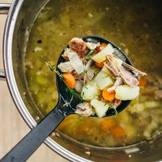 a ladle full of soup with meat and vegetables