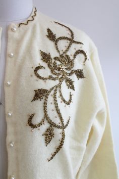 "Vintage 1970s pale yellow sweater with bronze and gold sequin details. The collar, hems, and cuffs are sequined. The front of the sweater has floral and swirl sequin designs. Faux pearl buttons down the front of the sweater for closure. Sweater in excellent wearable condition, little to no damage. Size small. Measurements Shoulders: 15.5\" / Sleeve Length: 19\" / Underarm to Underarm: 22\" / Length (Shoulder to Hem): 21\" Sweater was photographed on a size 2 mannequin. Unless otherwise stated a Elegant Gold Cardigan For Winter, Elegant Gold Winter Cardigan, Elegant Gold Sweater For Winter, Elegant Gold Winter Sweater, Fitted Gold Sweater For Spring, Vintage Embroidered Beige Sweater, Vintage Beige Embroidered Sweater, Vintage Embroidered Cream Cardigan, Vintage Cream Embroidered Cardigan