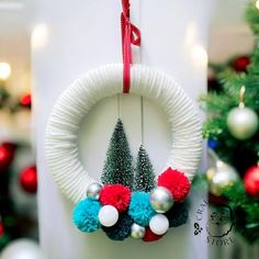 a white wreath with red, white and blue pom - poms hanging from it