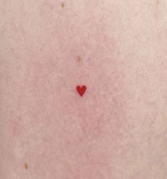 a small red heart on the back of someone's stomach with it's skin showing