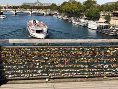 a bridge with many locks attached to it and a boat in the water next to it