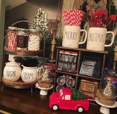 a shelf filled with mugs and other items on top of a wooden table next to a christmas tree