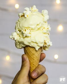 a hand holding an ice cream cone with white toppings