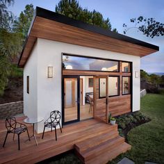 a small white house with wooden steps leading up to the front door and patio area