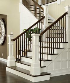 there is a clock on the wall next to some stairs and railings in this house