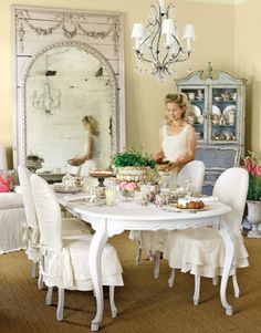 a woman standing in front of a white table with food on it and chairs around it