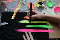 a woman is painting on a piece of black paper with bright colors and brush strokes