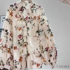 a white shirt with flowers is hanging on a rack