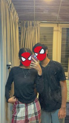 a man and woman taking a selfie in front of a mirror with spiderman masks on