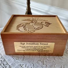 a wooden box with an eagle and globe etched on the lid is sitting on a white tablecloth