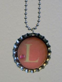 a bottle cap necklace with the letter l on it