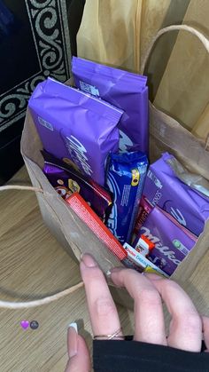 a person is holding a bag full of snacks and candy while sitting at a table