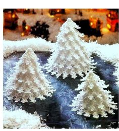 three snow covered trees sitting on top of a table