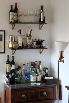 there are many bottles and glasses on the shelf above the bar counter in this room