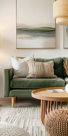 a living room with green couches and paintings on the wall above them, along with coffee table