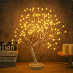 a lighted tree on a table next to some books