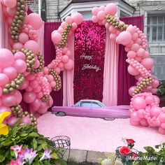 a pink car is parked in front of a birthday party entrance with balloons and streamers