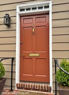 a red door on the side of a house with two planters in front of it