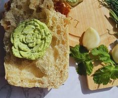 an avocado sandwich is sitting on a cutting board next to garlic and parsley