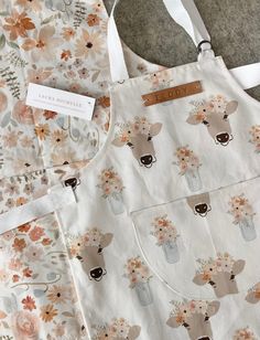 two aprons that have flowers on them and one has a cow in a mason jar