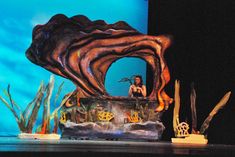 a stage set with an octopus on it's head and some plants in the background