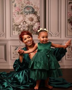 a woman in a green dress is holding a small child on her lap and smiling at the camera