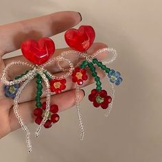 two red heart shaped brooches are being held in someone's hand,