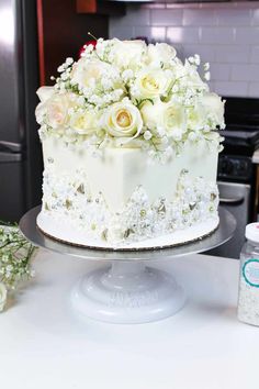 a white cake with flowers on it sitting on a table next to a bottle of water