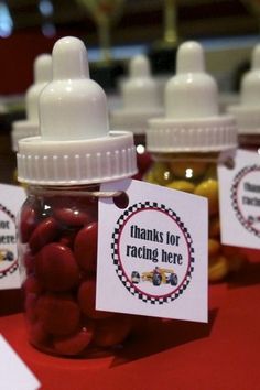 small jars filled with red and yellow candies sitting on top of a table next to each other