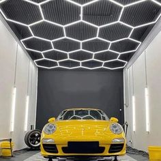 a yellow sports car parked in a garage under a metal structure with lights on it