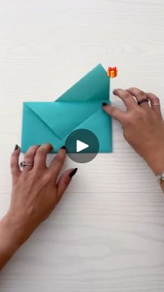 two hands are holding an origami envelope and one hand is opening the envelope