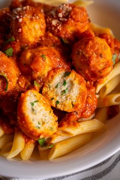 pasta with meatballs and parmesan cheese in a white bowl on a table