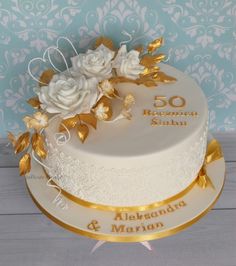 a white and gold wedding cake with flowers on top