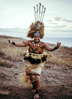 a woman dressed in native american clothing and headdress is dancing on the beach