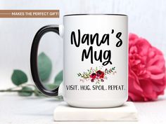 a coffee mug with the words nana's mug on it next to a pink flower