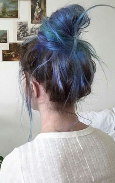 a woman with blue hair is standing in front of a wall full of pictures and photos