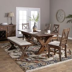 a dining room table with chairs and a bench in front of it on top of a rug